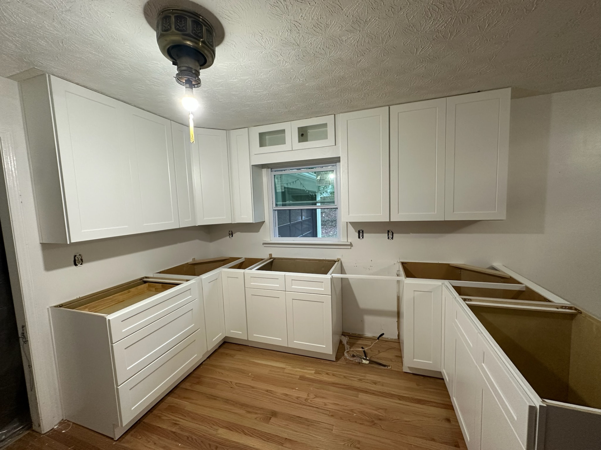 Compact U-shaped kitchen in Lawrenceville, GA with white shaker cabinets reaching the ceiling and deep drawer bases mid-install