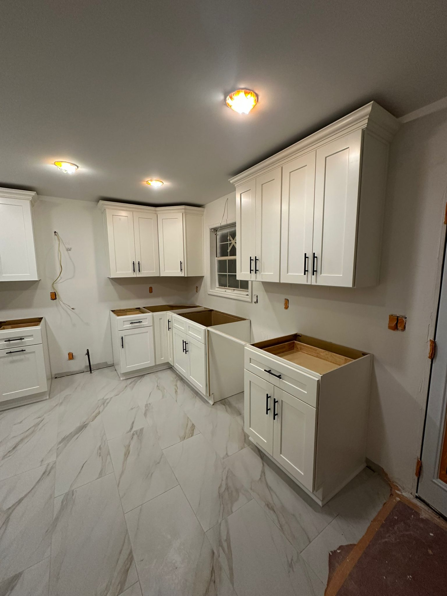 White shaker kitchen cabinets with stepped crown molding and black hardware installed in an Atlanta-area kitchen remodel