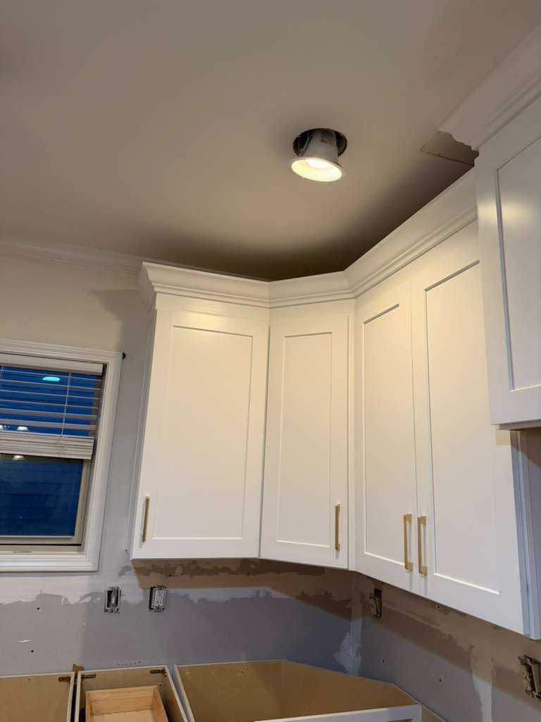 Close-up of white kitchen cabinet crown molding meeting the ceiling at a corner in an Atlanta-area kitchen