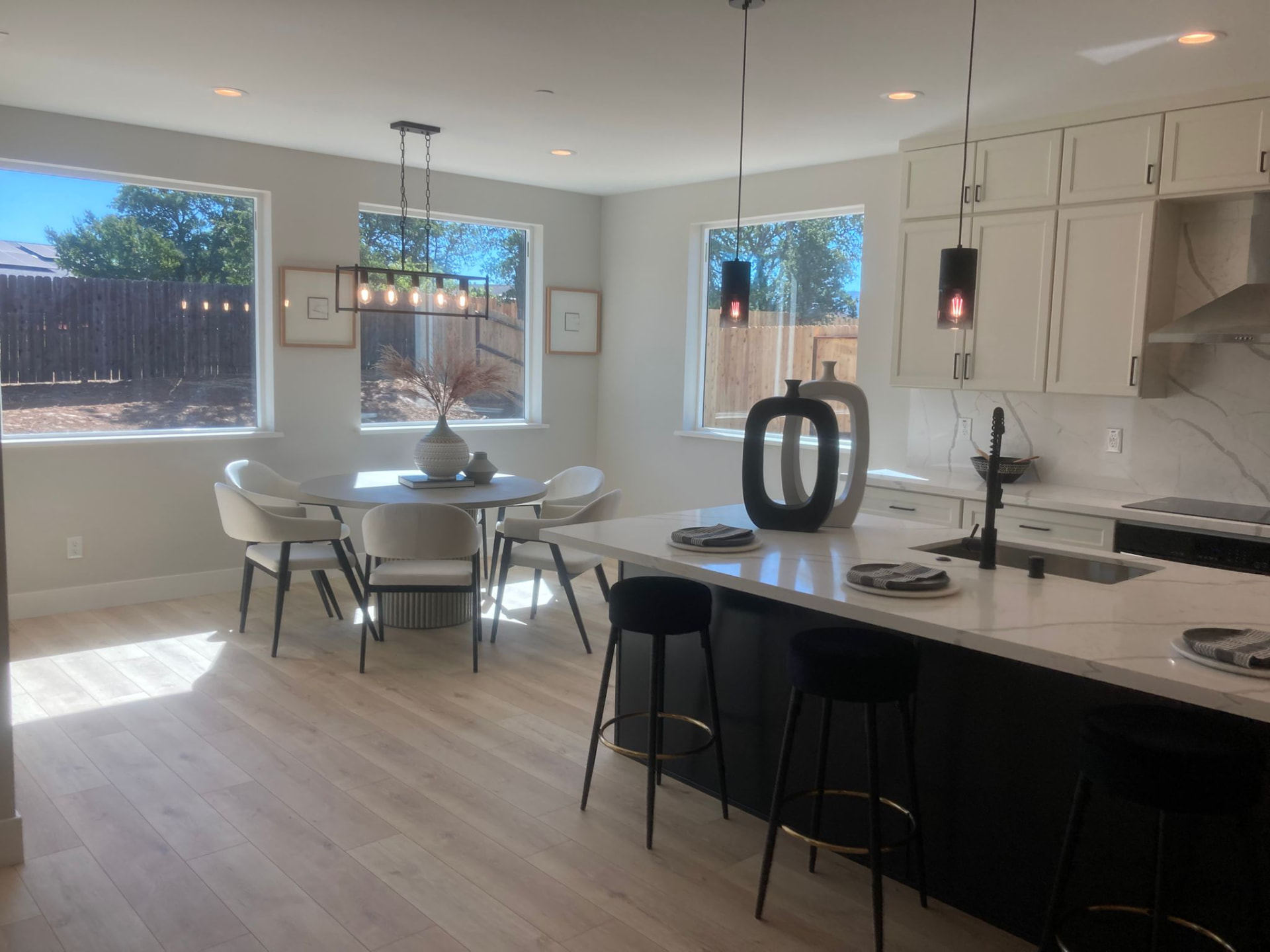 Modern white kitchen with black quartz-topped island, bar stools, and marble-look backsplash in an open-plan Suwanee, GA home